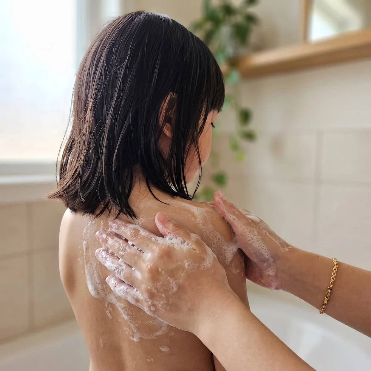 Lathering Head-to-Toe Wash over a child’s shoulders